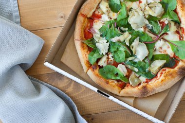 Tahta masada domatesli, peynirli ve mantarlı taze pizza.