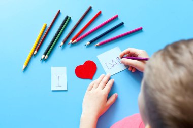 Babalar günü kompozisyonu. Beyaz kurdeleli hediye kutusu, bıyık, şapka ve el aletleri mavi arka planda. Üst görünüm düz, metin için boş alan var. Erkekler Günü ya da İşçi Bayramı için tebrik kartı.