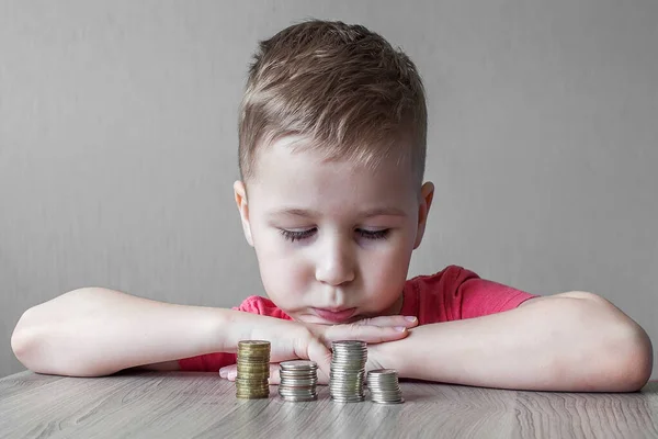 Cute little boy holding one pound coin and looking at money with smiling face, Happy boy wearing mismatched clothes with smiling face after got one pound for donation, Children development