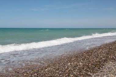 İnanılmaz sahil günbatımı sonsuz ufuk ve uzakta yalnız figürler, arkada volkanik tepeler..