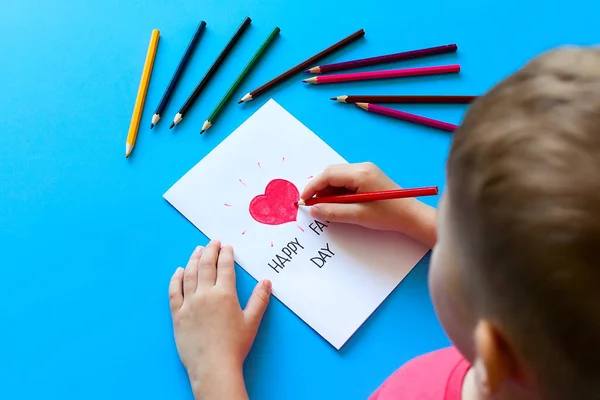 父の日だ 少年は鉛筆で父に絵葉書を書いています 子供の愛 — ストック写真