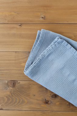 Yukarıdan keten mutfak havlu veya Tekstil peçete ile kahverengi ahşap masa görüntüleyin. Koyu kahverengi ahşap masa üzerinde mavi masa örtüsü. Metin için yer kopyalayın. Tasarım için sahte olarak kullanabilirsiniz