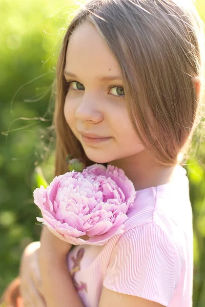 戴着雀斑的女孩在花园里摆设着牡丹花 — 图库照片