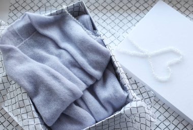 Pastel renkli kadın kıyafetleri beyaz arka planda bir kutunun içinde katlandı. Hediye organizasyonu konsepti.