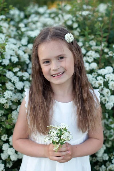 白いドレスの女の子が白い花の花束を持って立っている 開花期 — ストック写真