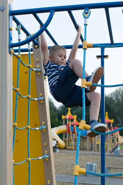 Açık havada çocuk parkında bir çocuk. İp merdiveni. Yaz günü