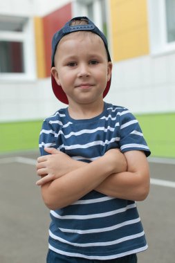 Sırt çantalı, gülümseyen küçük bir çocuk atlıyor ve mavi duvara karşı eğleniyor. Kameraya bakıyorum. Okul konsepti. Okula Dönüş