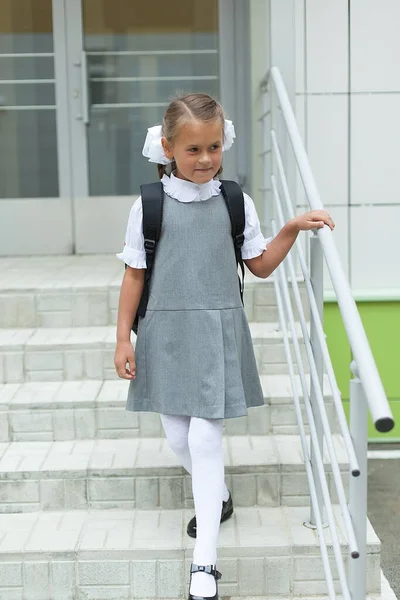 A first-grader walks up the steps of the school. Day of knowledge. September 1.