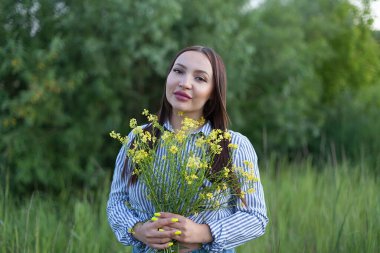 Güzel, orta yaşlı sarışın bir kadının açık hava portresi. Çiçeklerle dolu bir tarlada çekici seksi bir kız.