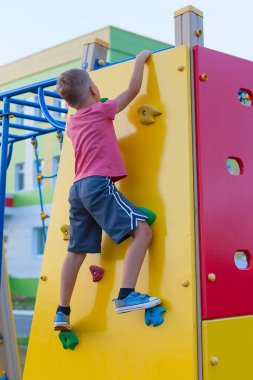 Oyun parkında kırmızı tişörtlü küçük bir çocuk. Açık hava oyunları. mobil oyunlar.