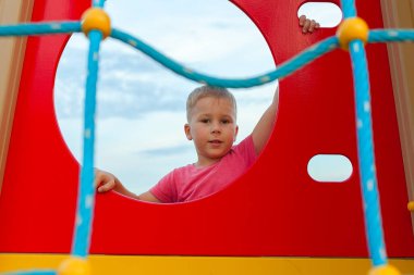 Oyun parkında kırmızı tişörtlü küçük bir çocuk. Açık hava oyunları. mobil oyunlar.