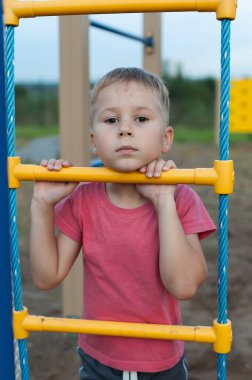 Küçük bir çocuk yaz günü çocuk parkında kaya tırmanışı yapıyor.