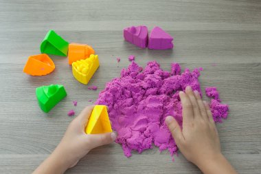 Bir çocuğun ellerinde parlak pembe kinetik kum. Geliştirme ve eğitim. İnce motor beceriler