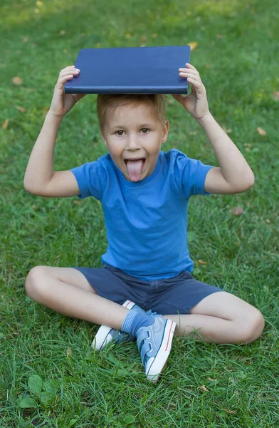 Um menino bonito está com um livro nas mãos. Fascinante livro infantil. Leitura de livros. — Fotografia de Stock