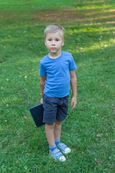 Um menino bonito está com um livro nas mãos. Fascinante livro infantil. Leitura de livros. — Fotografia de Stock