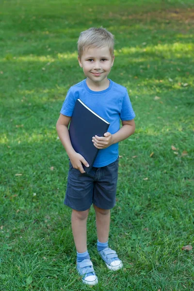 Um menino bonito está com um livro nas mãos. Fascinante livro infantil. Leitura de livros. — Fotografia de Stock