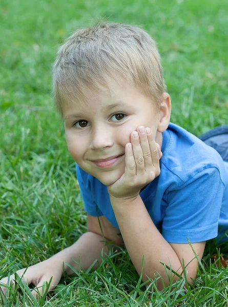 Zeven jaar oud kind dat een boek leest liggend op het gras — Stockfoto