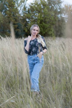 Buğday tarlasında şehvetli bir kız. Genç ve güzel bir kadın kameraya bakar.