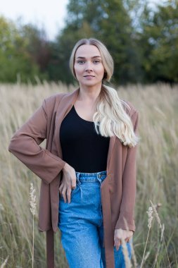 Gün batımında tarlada genç ve güzel bir kadın. Açık havada yürümek. kadınlık