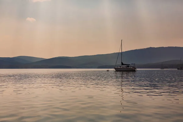 Sailing boat in the lake in the evening sunlight over the beautiful big mountains background, luxury summer adventure, active holidays in the Mediterranean sea, Turkey