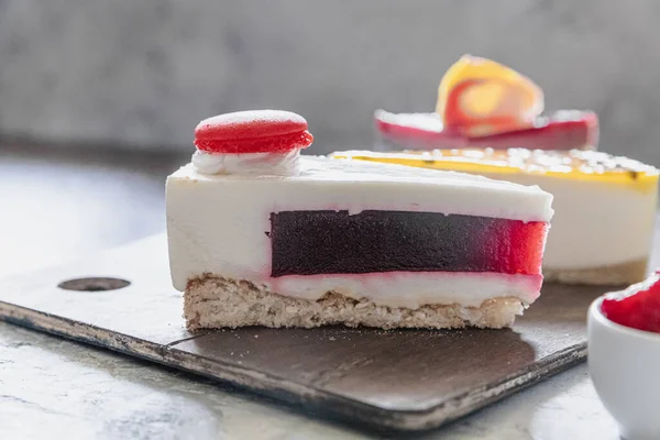 A delicious piece of raspberry and berry mousse cake, pink macaroon on top. Juicy mouth-watering dessert with jelly — Stock Photo, Image