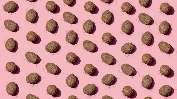 Whole coconuts pattern on a pink background with hard shadows. Print for clothes, packaging