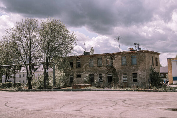 Abandoned places, a post-apocalyptic concept. An old metal mug hangs on a rusty pole against the background of a vacant lot