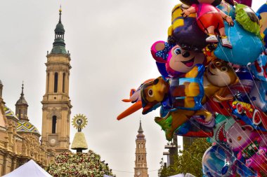 Saragossa, Spain - October 12, 2017: View of the Plaza del Pilar on the day of the flower offering with the domes and towers of the Basilica of Nuestra Senora del Pilar, La Seo and some children's balloons. clipart