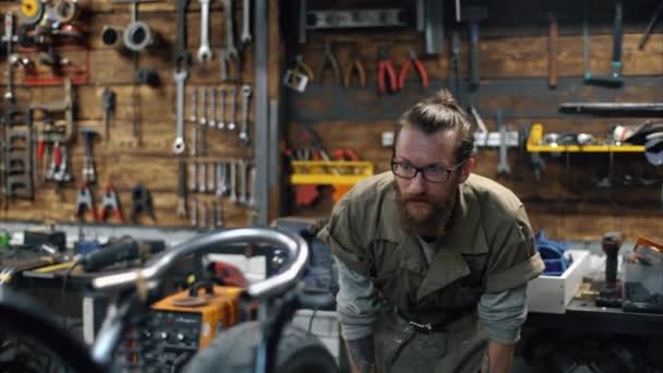 Reparando bicicleta. Hombre con barba están creando motocicleta personalizada — Vídeos de Stock