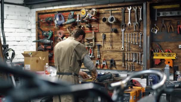 Reparando bicicleta. Hombre con barba están creando motocicleta personalizada — Vídeo de stock