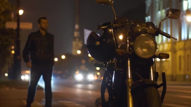 Байкер сидит на мотоцикле и надевает шлем в замедленной съемке. — стоковое видео