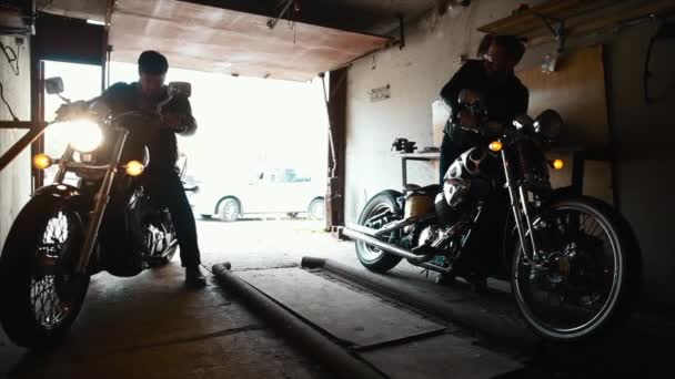 Zwei Biker bringen maßgeschneiderte Motorräder in die Garage — Stockvideo