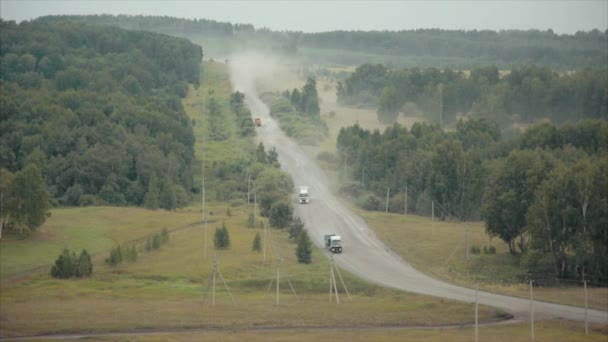 Camiones que viajan por una carretera entre bosques . — Vídeos de Stock