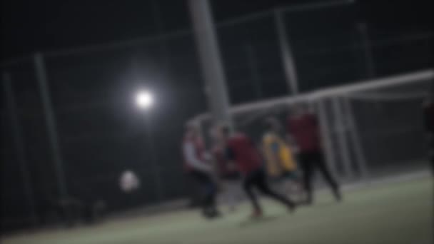 Borroso de hombres jugando al fútbol al aire libre en la noche . — Vídeos de Stock