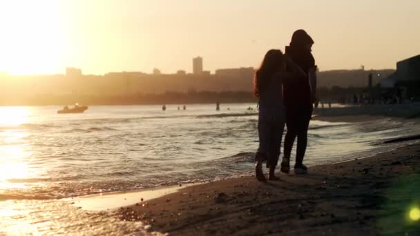 Gyerekek sétálnak a strandon napnyugtakor. — Stock videók