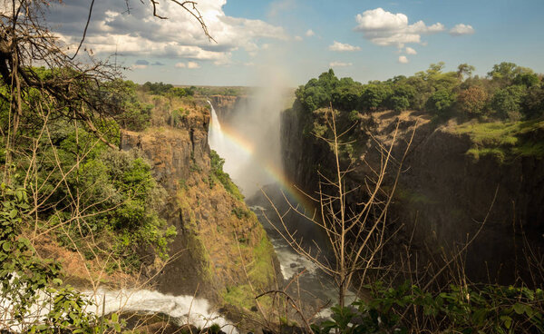 Rainbow over Victoria Falls on Zambezi River. Victoria falls is a waterfall in southern Africa on the Zambezi River at the border of Zambia and Zimbabwe.