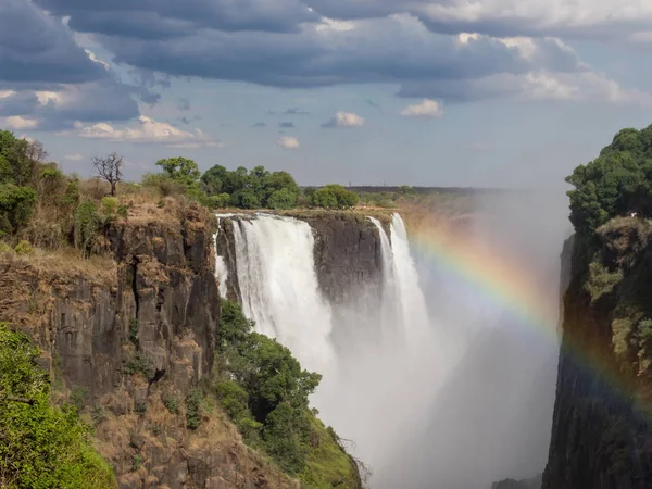 Rainbow over Victoria Falls on Zambezi River. Victoria falls is a waterfall in southern Africa on the Zambezi River at the border of Zambia and Zimbabwe.