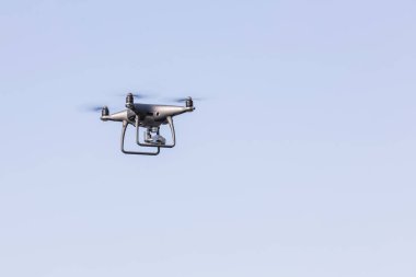 Dönen pervanelerle insansız hava aracıyla bir el indirin. Mavi gökyüzünde uçan drone.