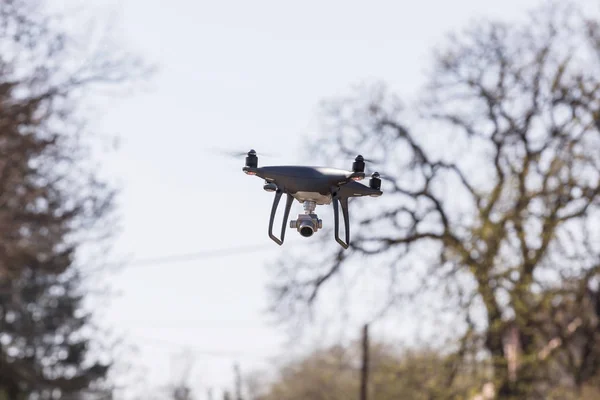 Atterraggio di una mano droned con eliche rotanti. Piccolo drone grigio che vola tra gli alberi . — Foto Stock