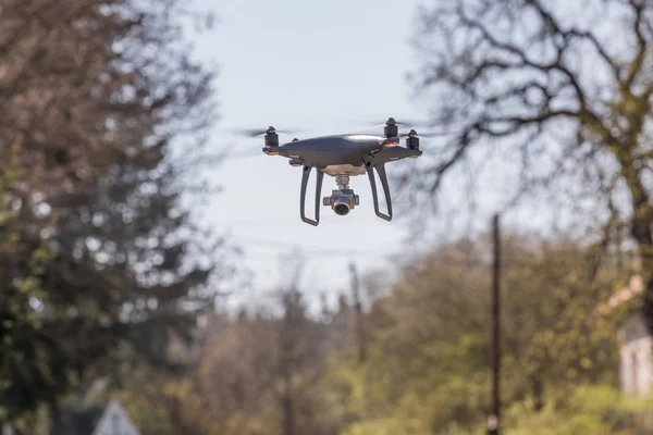 Atterraggio di una mano droned con eliche rotanti. Piccolo drone grigio che vola tra gli alberi . — Foto Stock