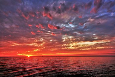 Karadeniz 'de muhteşem bir gün batımı. Güneş ufukta batıyor. Deniz ve bulutlar parlak kırmızı, altın, pembe, leylak, mor ve mavi renklerde boyanmıştır. Bulutlar gül yaprakları gibidir. Renk ziyafeti.