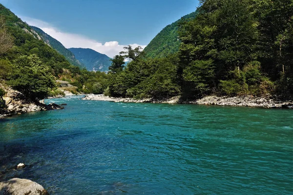 一条碧绿的河流流过布满森林的山岗之间 海岸是岩石 水是翻腾的 明亮蓝天上的云彩 阿布哈兹 — 图库照片