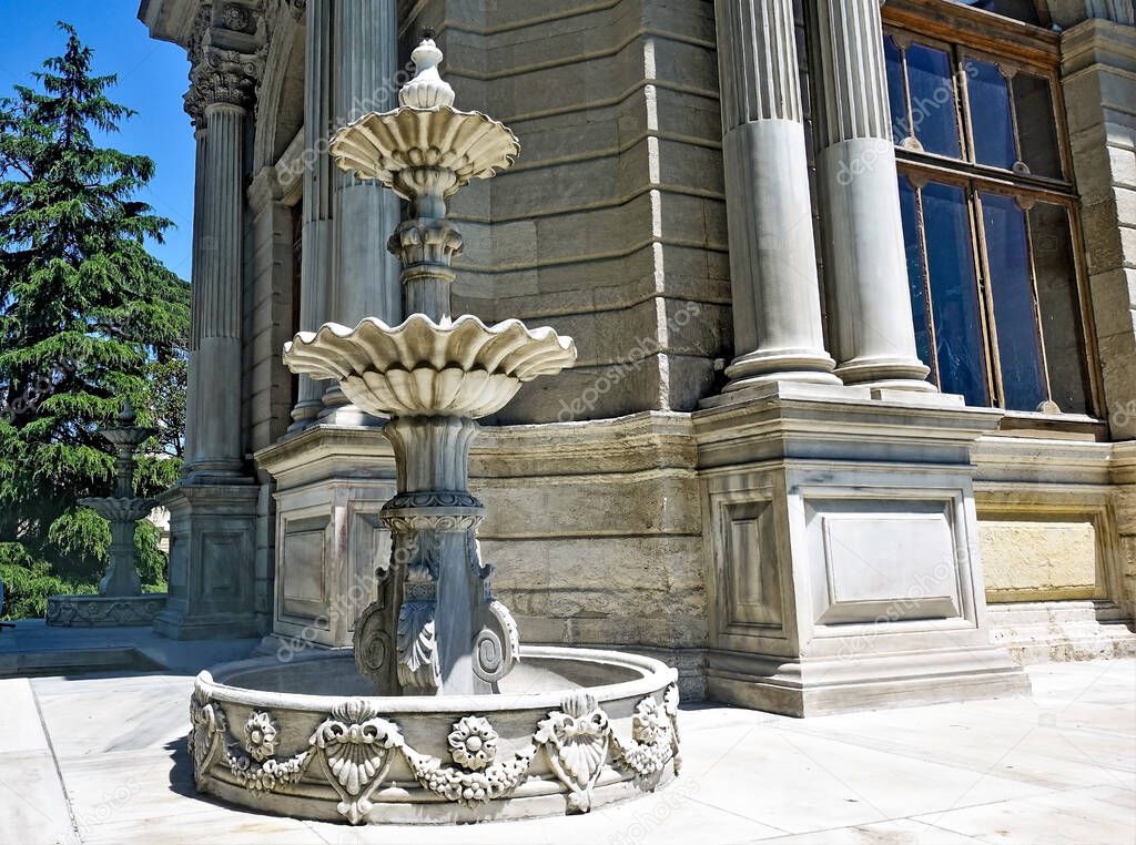 Marble three-tier graceful fountain in the garden of Dolmabahce Palace. Bowls of the fountain in the form of opened flowers. Beautiful stone carving on the base. Istanbul. Turkey.