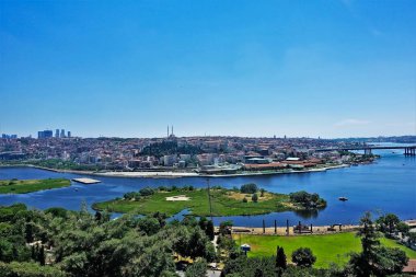 İstanbul Panoraması, yaz güneşli bir gün. Parlak mavi Haliç Koyu, yeşil adalar. Uzakta birçok yerleşim yeri, gökdelenler, camiler var. Açık mavi gökyüzü. Türkiye.