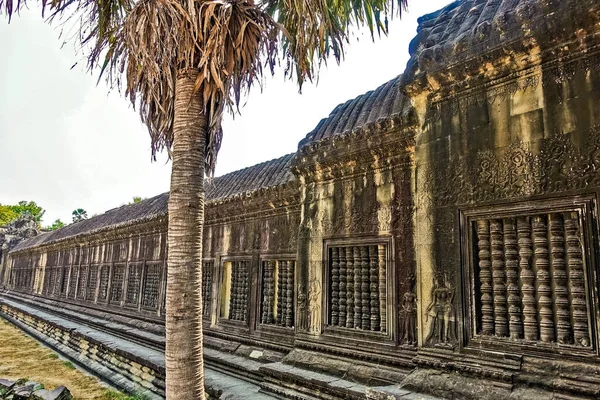 The famous temple of Angkor. The ancient long gallery is well preserved. The walls are decorated with ornaments, bas-reliefs of apsara dancers. The window openings are covered with stone bars.Cambodia