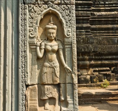 Benzersiz Angkor tapınağında kadim bir yardım. Tapınağın taş duvarına ayrıntılı olarak bir kadın figürü oyuluyor. Süslerle süslenmiş. Unesco mirası. Kamboçya. Angkor.