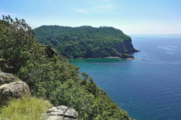 前景是一个有大石头的山体斜坡 在绿松石色的安达曼海可以看到一个绿色的岛屿 晴朗的蓝天 — 图库照片