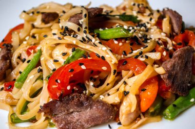 Beyaz arka planda sebze ve etten oluşan Pad Thai.