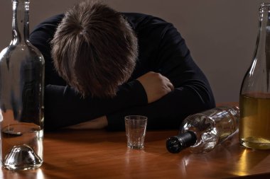 Sarhoş bir adam masada uyuyor. Alkolizm, alkol bağımlılığı ve depresyon.