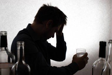 Bir adam ve bir bardak votka. Alkolizm, alkol bağımlılığı, sayıklamalar. Siluet fotoğraf.